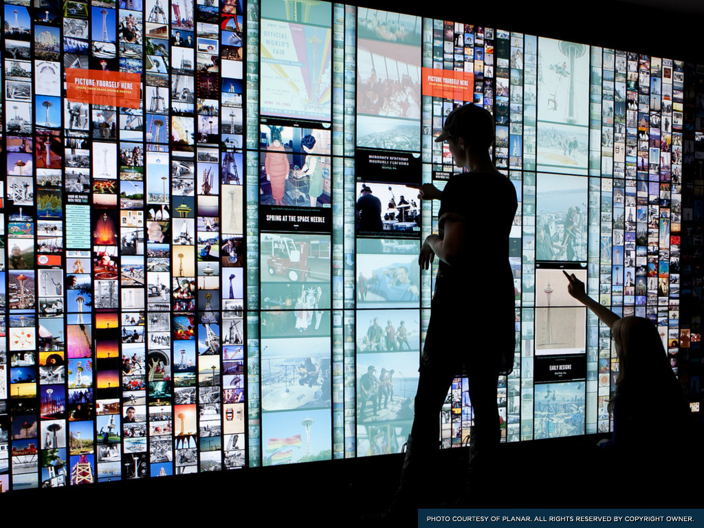 Visitors exploring photos with fine touchscreen controls at the Space Needle in Seattle, Washington.